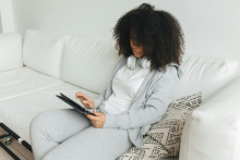 Woman sitting on sofa using a tablet device